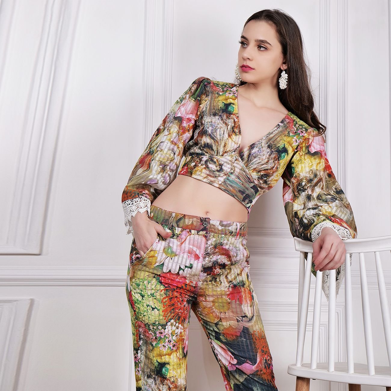 Fashionable woman posing in a colorful floral outfit in a studio setting.